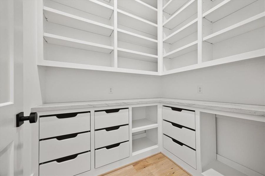 WALK-IN PANTRY: No detail has been spared in ensuring ample space for your pantry essentials. Custom shelves accommodate everything from spices to canned goods, while pull-out drawers offer a sleek solution for easy storage and retrieval. This space is more than just a pantry; it's a culinary command center designed to enhance your daily life.