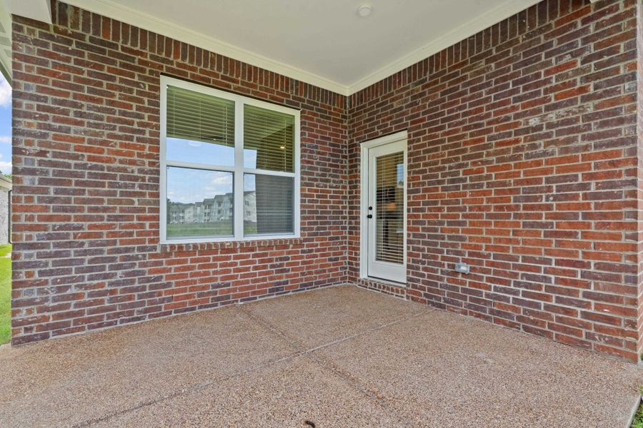 Covered patio featuring brick exterior, exposed aggregate concrete flooring, recessed lighting, a multi-pane window with blinds, and a glass-paneled exterior door Covered patio featuring brick exterior, exposed aggregate concrete flooring, recessed lighting, a multi-pane window with blinds, and a glass-paneled exterior door