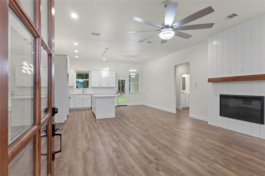Open-concept interior featuring wood-finish flooring, a contemporary ceiling fan, and recessed lighting Open-concept interior featuring wood-finish flooring, a contemporary ceiling fan, and recessed lighting