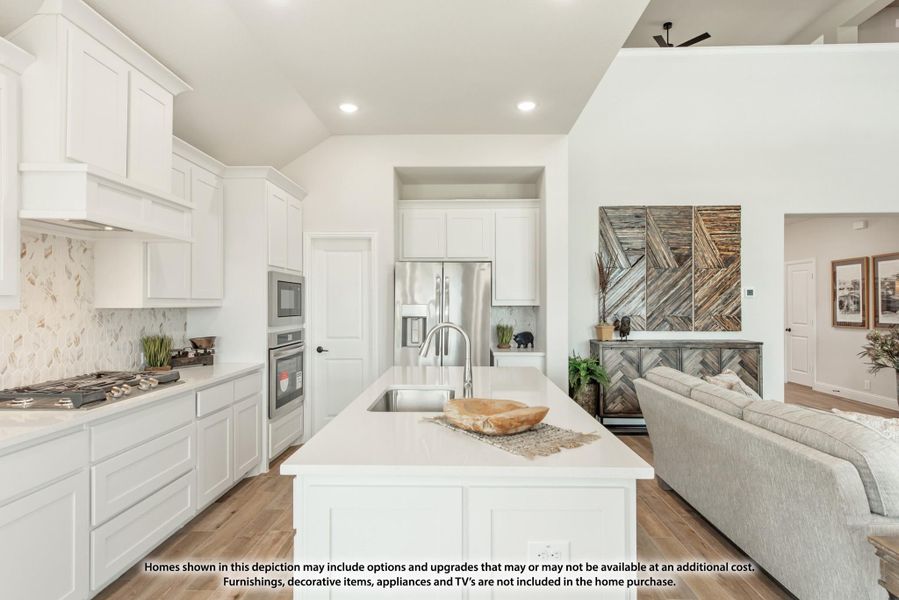 Open kitchen with white cabinets, center island, stainless appliances, and wood floors opening to living room