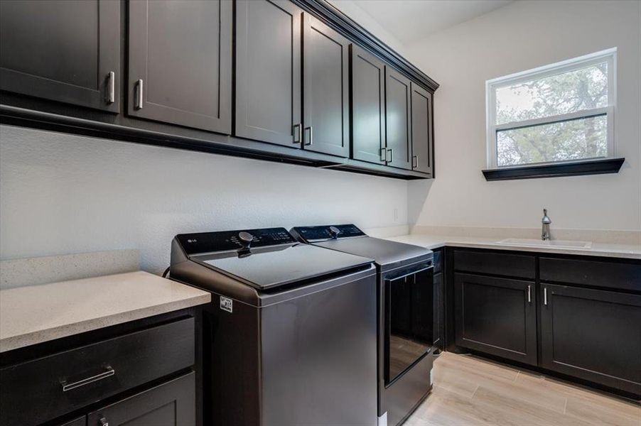 Laundry room with cabinet space, light tile-style flooring, and separate washer and dryer