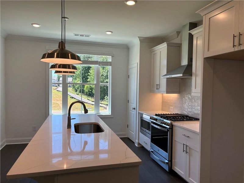 Beautifully appointed kitchen:  quartz counter tops, designer backsplash, pendant lights...GE appliances.