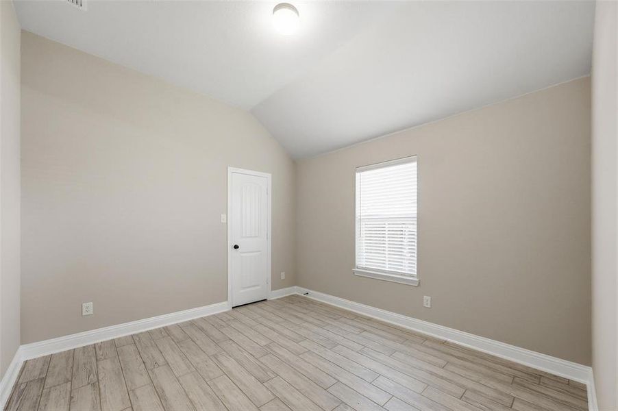Spare room featuring wood tiled floors and lofted ceiling Spare room featuring wood tiled floors and lofted ceiling