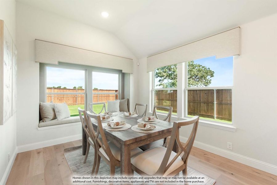 Dining area with wood table, four chairs, window seat, and large windows overlooking fenced backyard