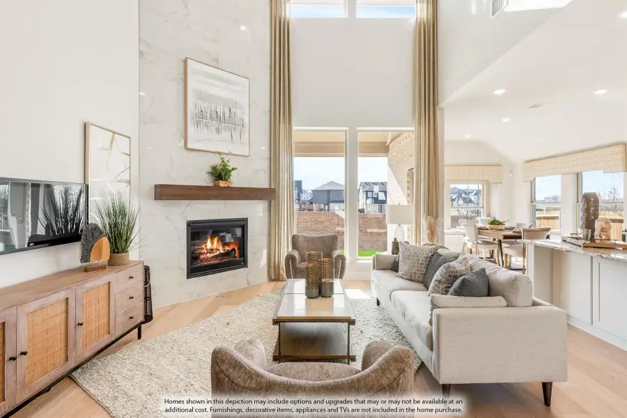 Open-concept living room with two-story ceiling, marble fireplace, and hardwood floors