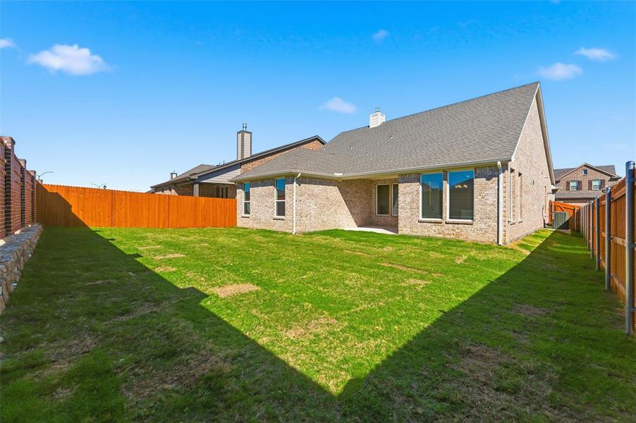 Back of house with a fenced backyard, a patio area, a chimney, brick siding, and roof with shingles
