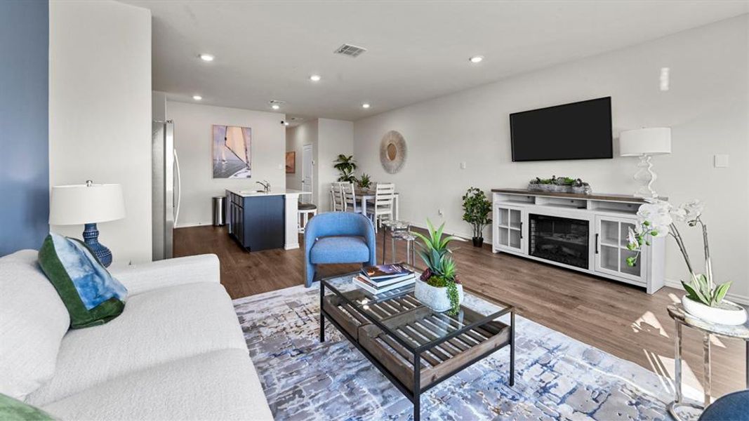 Open-concept living area featuring wood-finish flooring, recessed lighting, and a neutral color palette
