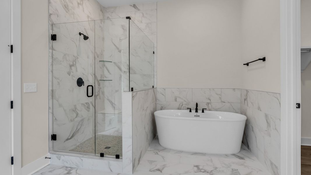 Primary bathroom with frameless glass and tiled shower and freestanding tub (Representative of completed home)