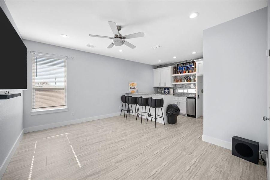Kitchen with a breakfast bar, a peninsula, open shelves, white cabinets, and a ceiling fan
