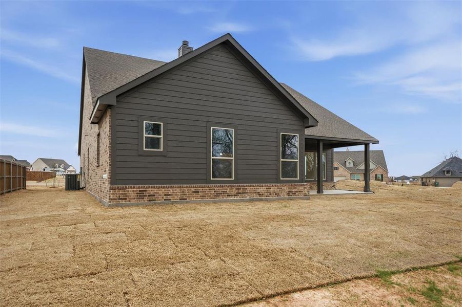 Back of house with brick siding, a patio, a chimney, and a shingled roof Back of house with brick siding, a patio, a chimney, and a shingled roof