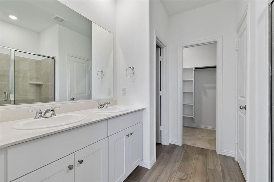 Bathroom with oversized vanity, an enclosed shower, hardwood / wood-style flooring, and dual sinks