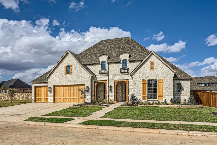 French country style house with a front lawn and a garage