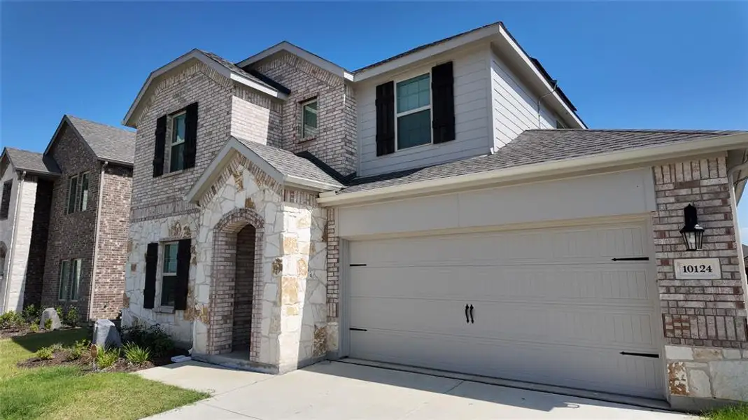 View of front of home with stone siding, a garage, brick siding, concrete driveway, and a shingled roof