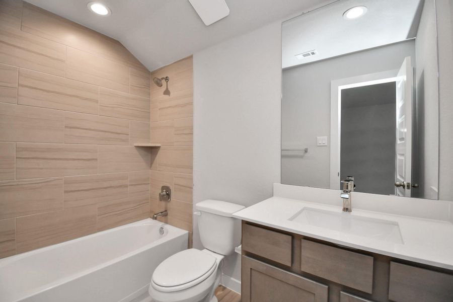 Secondary bath features tile flooring, bath/shower combo with tile surround, light stained wood cabinets, beautiful light countertop. Secondary bath features tile flooring, bath/shower combo with tile surround, light stained wood cabinets, beautiful light countertop.