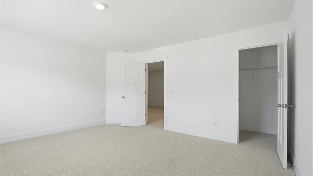 Vibrant and inviting secondary bedroom featuring a walk-in closet and refined finishes located at Village at Midway Vibrant and inviting secondary bedroom featuring a walk-in closet and refined finishes located at Village at Midway
