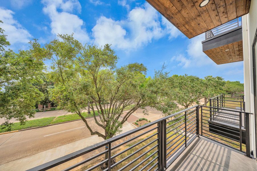 Balcony with sleek railing, offering a view of a tree-lined street and clear blue skies, perfect for enjoying outdoor relaxation. Balcony with sleek railing, offering a view of a tree-lined street and clear blue skies, perfect for enjoying outdoor relaxation.