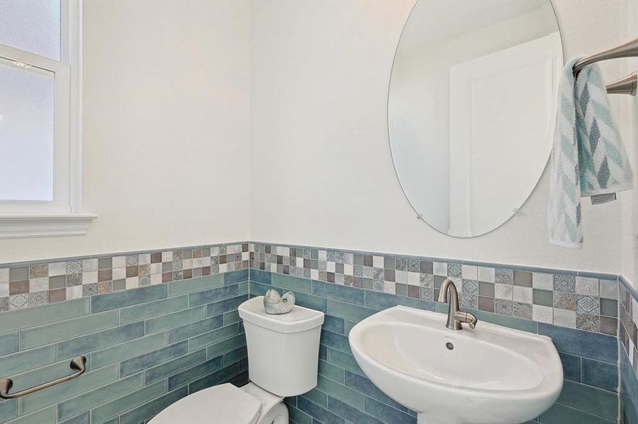 Bathroom with tile walls, sink, tasteful backsplash, and toilet