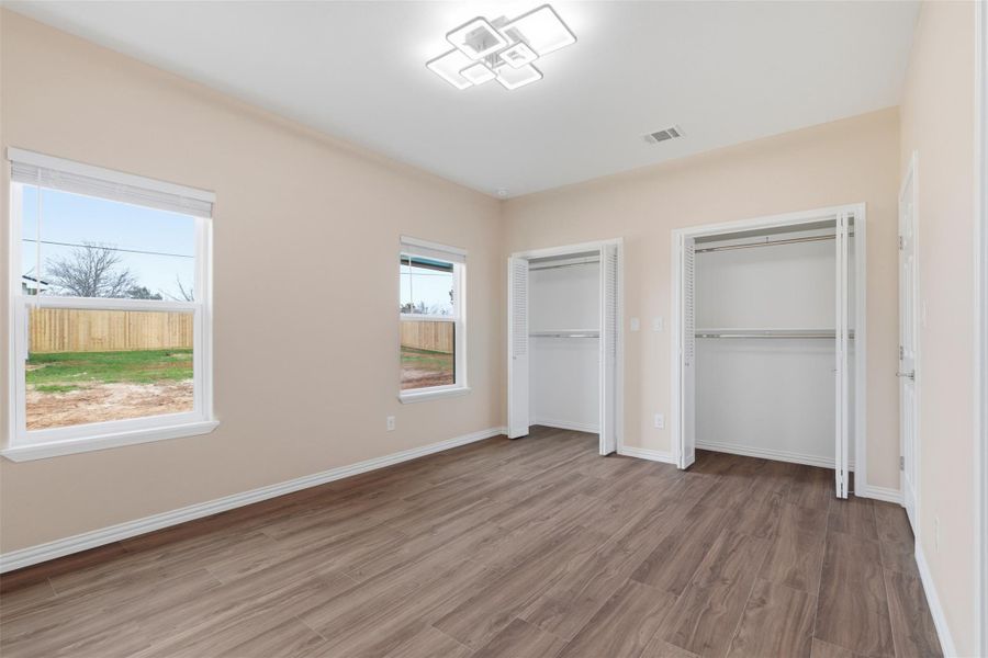 Unfurnished bedroom featuring two closets and wood finished floors
