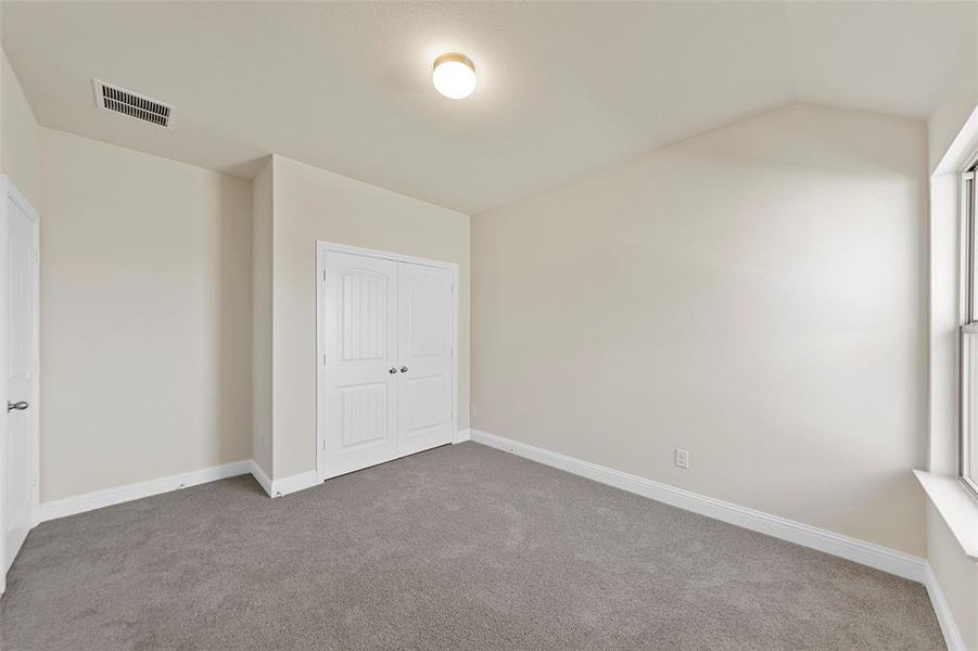 Unfurnished bedroom with a closet, carpet, and lofted ceiling