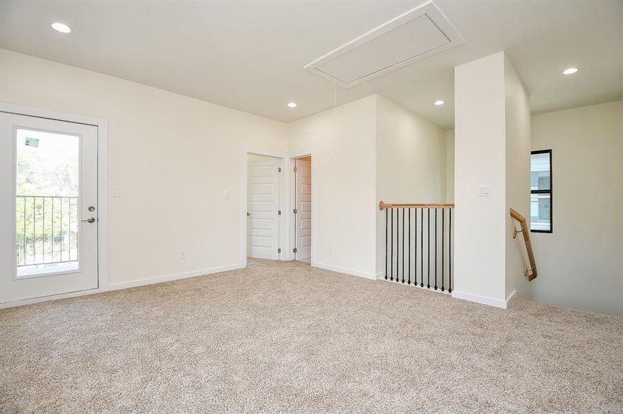 Ascend to the second-floor landing from this staircase, where a welcoming game room area awaits, complete with plush carpet and a stylish private balcony.