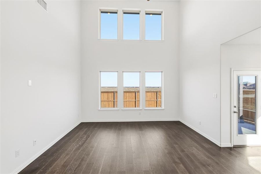 Vaulted ceiling room featuring wood-finish flooring, six windows, and a glass-paneled exterior door