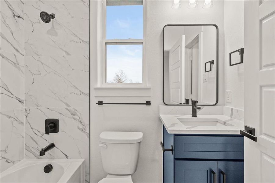 Full bathroom with vanity, tiled shower / bath combo, and toilet