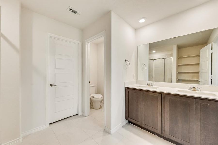 Full bathroom with a stall shower, double vanity, light tile patterned flooring, recessed lighting, and a closet Full bathroom with a stall shower, double vanity, light tile patterned flooring, recessed lighting, and a closet