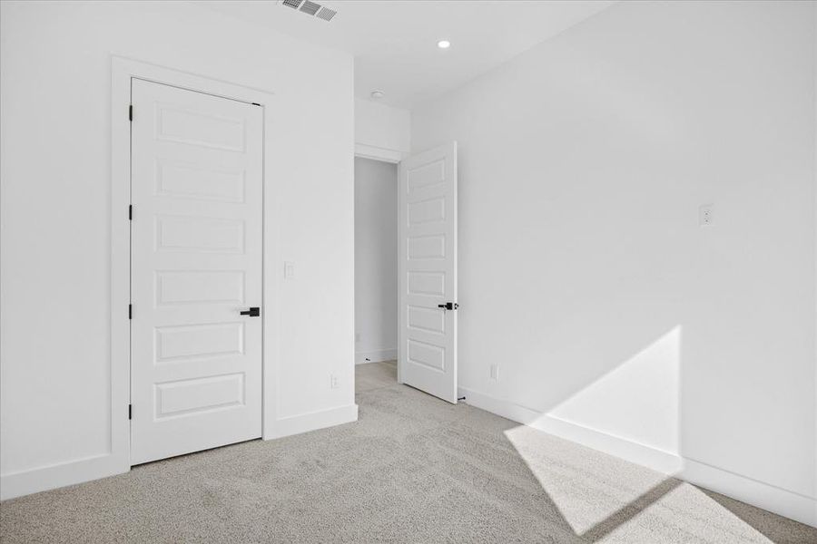 Carpeted Master/owner good size bedroom with white walls, baseboards, and a modern five-panel door featuring a matte black handles/hardwares