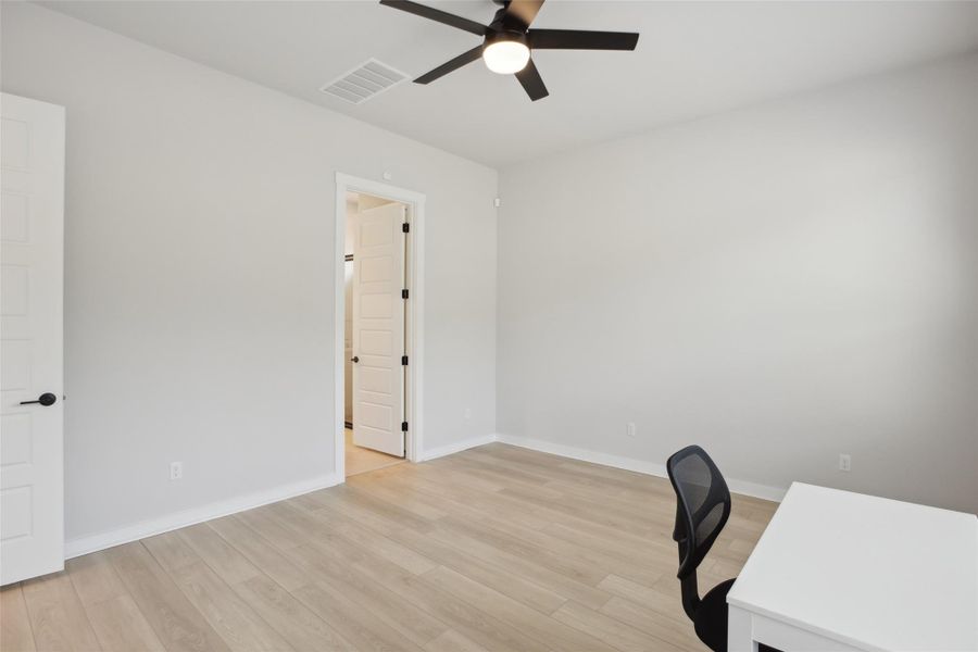 Office area with a ceiling fan, light wood-type flooring, visible vents, and baseboards