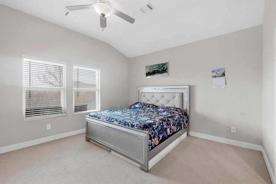Carpeted bedroom with vaulted ceiling and a ceiling fan Carpeted bedroom with vaulted ceiling and a ceiling fan
