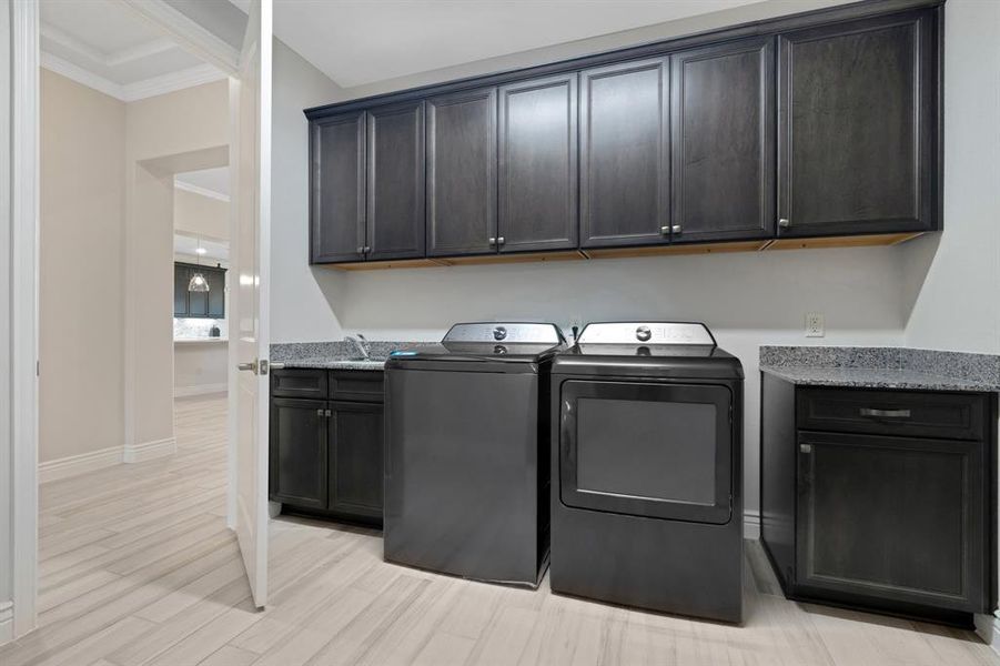The utility room has lots of cabinets and a sink!