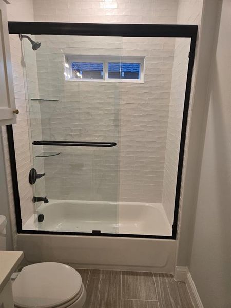 Bathroom featuring toilet and combined bath / shower with glass door