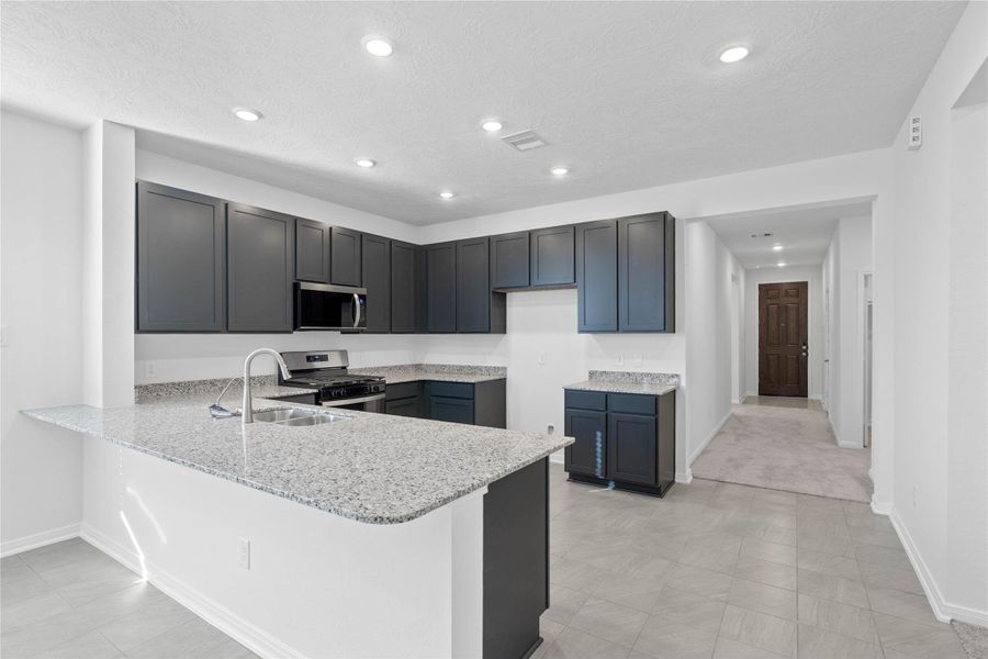 The kitchen exudes warmth with stunning Black Mist granite countertops perfectly paired with the rich, inviting tone of the Woodmont cabinetry in a Ginger stain. This combination creates a truly gorgeous and cohesive aesthetic.