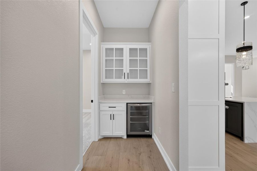 A built-in wet bar alcove features custom glass-front cabinets and hard surface flooring.