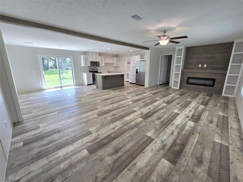 Step into a spacious open-concept living room and kitchen, where rustic wood flooring meets modern amenities, and natural light pours in through large glass doors, creating an inviting and airy atmosphere perfect for both relaxation and entertainment. Step into a spacious open-concept living room and kitchen, where rustic wood flooring meets modern amenities, and natural light pours in through large glass doors, creating an inviting and airy atmosphere perfect for both relaxation and entertainment.
