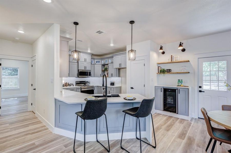 Kitchen with pendant lighting, stainless steel appliances, sink, and light hardwood / wood-style flooring