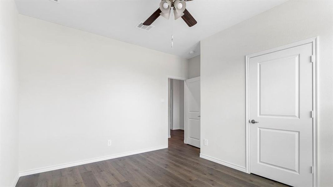 Bright room with wood-finish flooring, white baseboards, and a ceiling fan