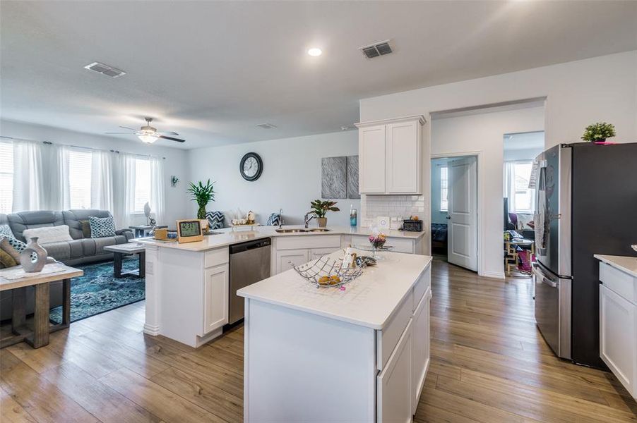 Kitchen with white cabinets, a center island, light hardwood / wood-style floors, and appliances with stainless steel finishes