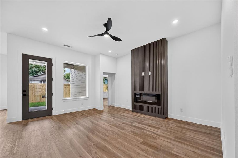 Spacious room featuring wood-finish flooring, a contemporary ceiling fan, and recessed lighting Spacious room featuring wood-finish flooring, a contemporary ceiling fan, and recessed lighting