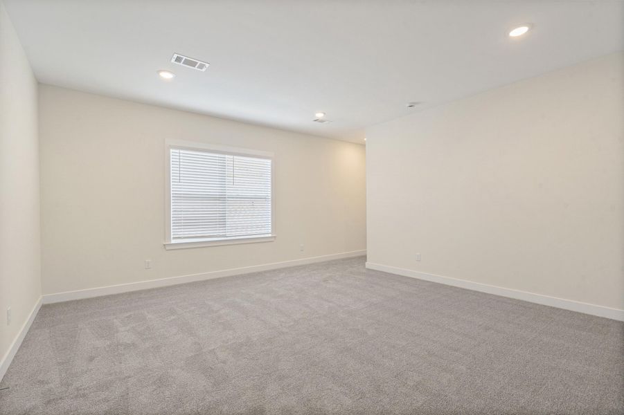 Spacious room featuring neutral carpeting, light-toned walls, and a window with blinds Spacious room featuring neutral carpeting, light-toned walls, and a window with blinds