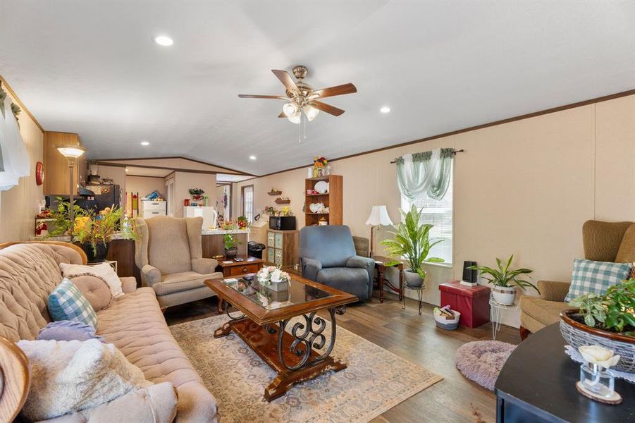 Living area with ceiling fan, lofted ceiling, ornamental molding, recessed lighting, and wood finished floors Living area with ceiling fan, lofted ceiling, ornamental molding, recessed lighting, and wood finished floors