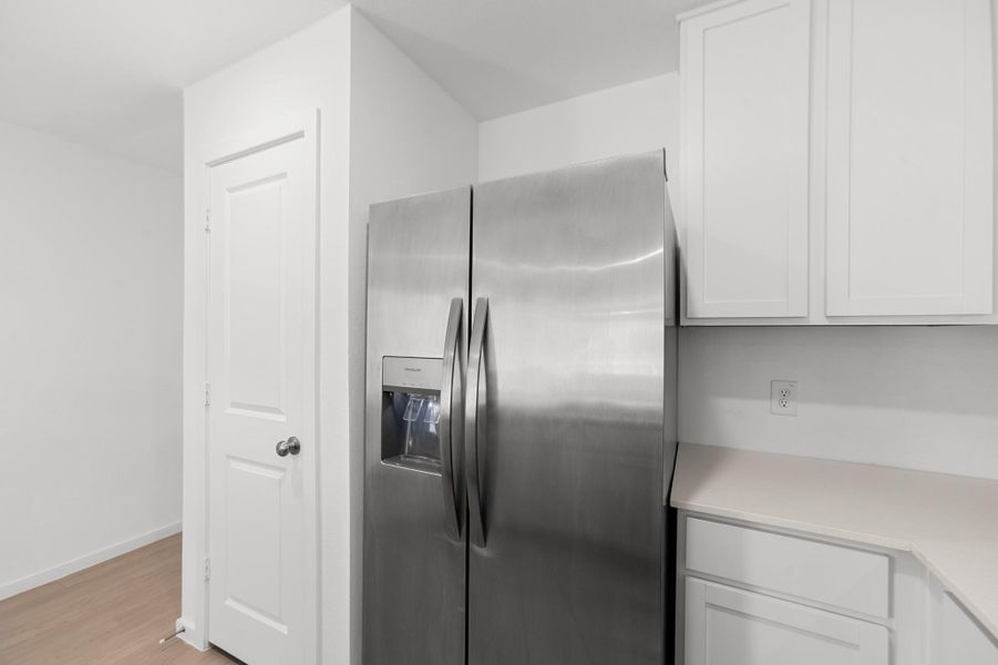 Stainless steel side-by-side refrigerator with in-door water and ice dispenser complements the crisp white cabinetry and adjacent countertop space. Stainless steel side-by-side refrigerator with in-door water and ice dispenser complements the crisp white cabinetry and adjacent countertop space.