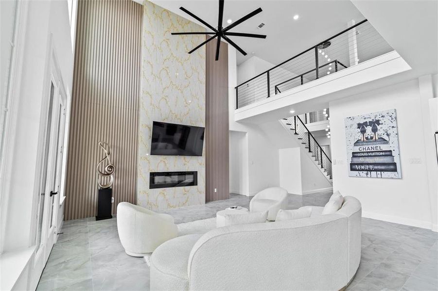 Living room featuring a premium fireplace, a high ceiling, stairs, and marble finish floors