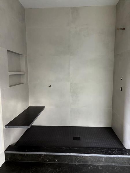 Primary Shower with 2 showers one handheld. Floating Granite bench.  double shelf storage in all 4 baths.