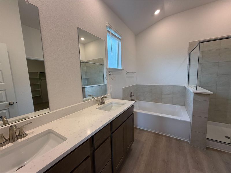 Full bath featuring dark wood-type flooring, a bath, double vanity, a shower stall, and recessed lighting