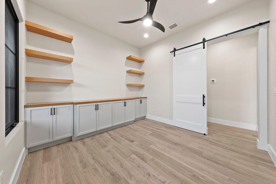 Functional built-in cabinetry and open shelving provide ample storage in this versatile space.
