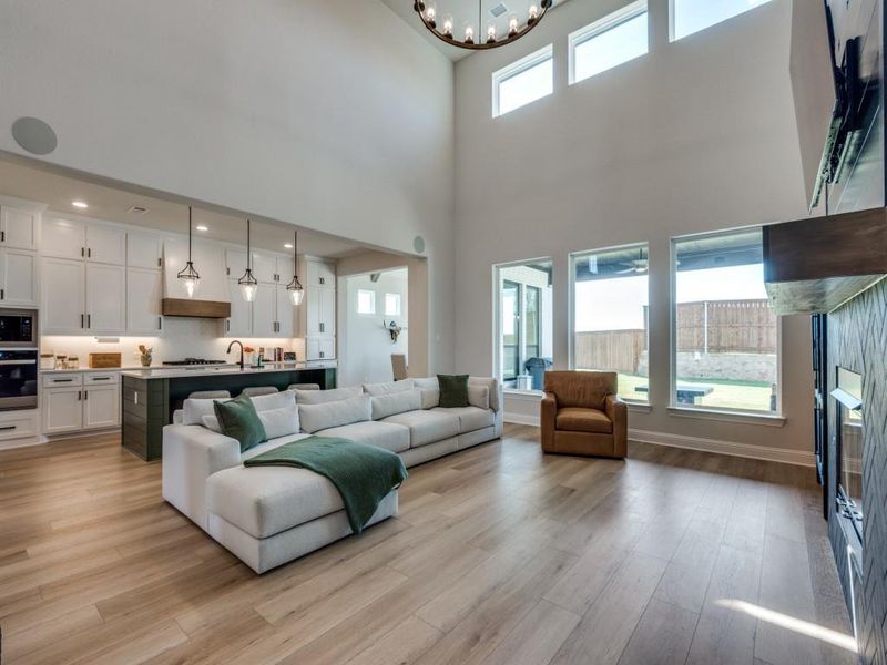 Living room featuring a fireplace, a high ceiling, a chandelier, and light wood-type flooring