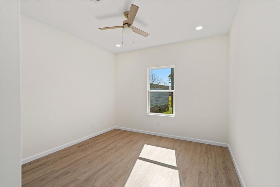 Bright secondary bedroom with ceiling fan, recessed lighting, and durable flooring.