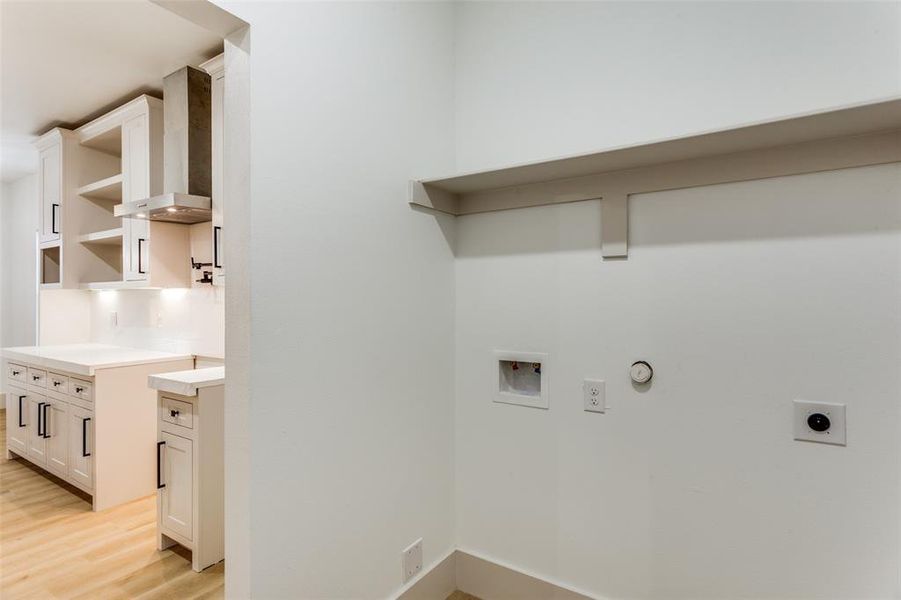 Laundry room featuring hookup for a gas dryer, washer hookup, electric dryer hookup, and light wood-style floors Laundry room featuring hookup for a gas dryer, washer hookup, electric dryer hookup, and light wood-style floors