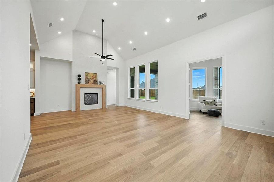 Unfurnished living room with high vaulted ceiling, a fireplace, a ceiling fan, light wood-type flooring, and recessed lighting